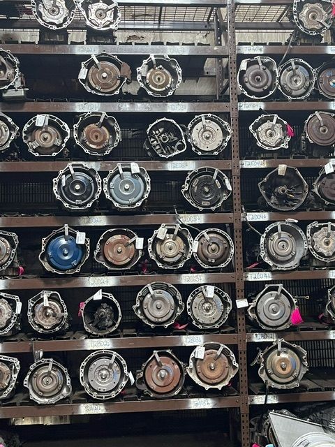 A storage rack filled with numerous automotive torque converters arranged on multiple metal shelves.