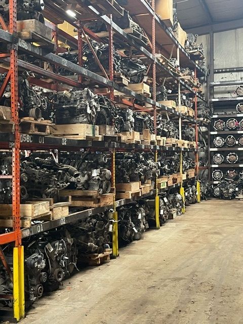 Rows of car engines stored on tall, metal industrial warehouse shelving.