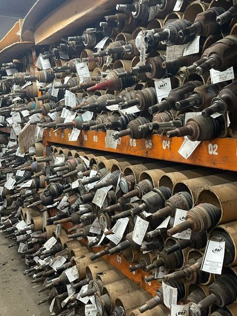 A warehouse storage rack filled with numerous automotive CV axles, each stored in individual cardboard tubes.