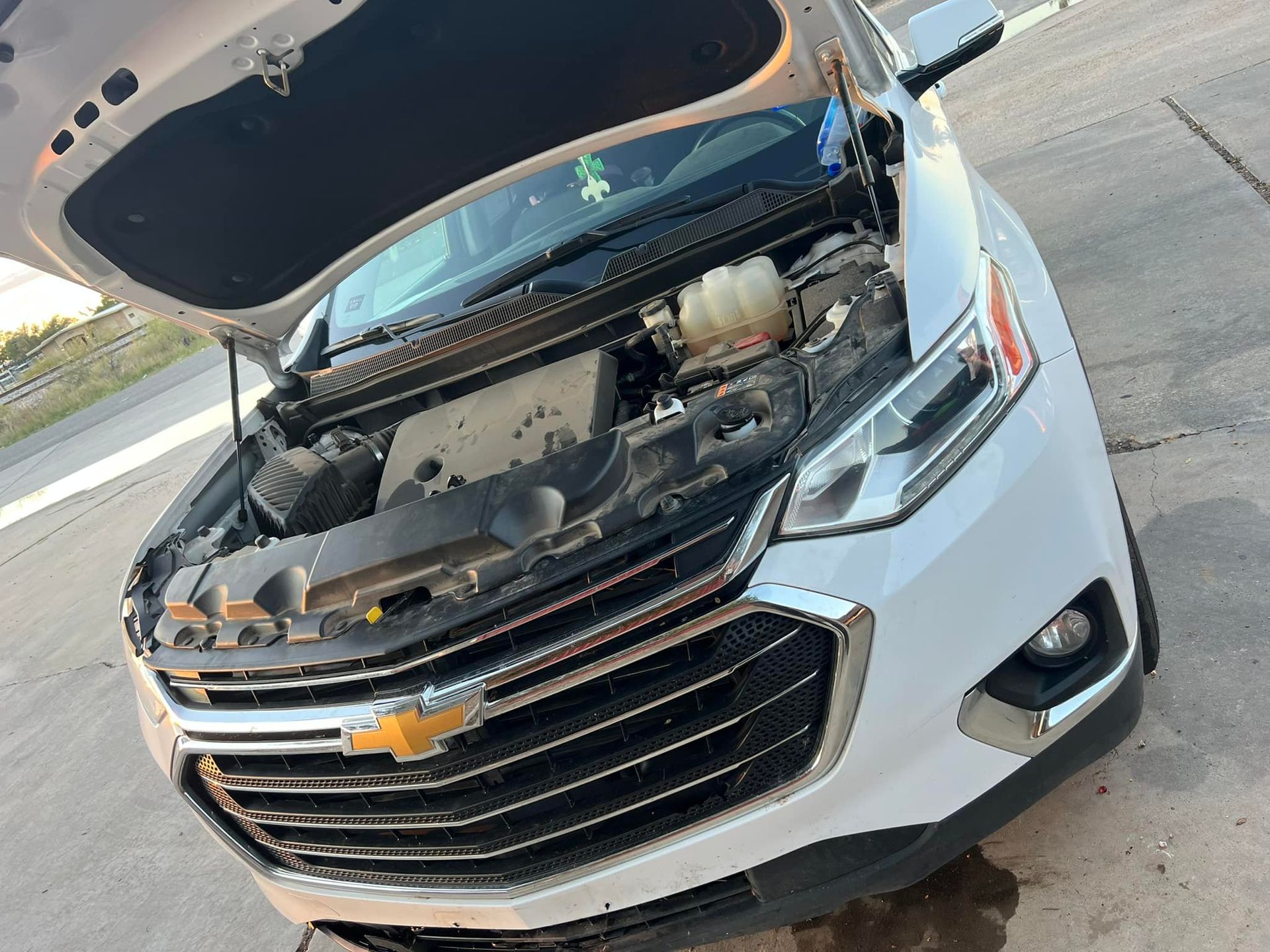White Chevrolet SUV with the hood open, parked outdoors.