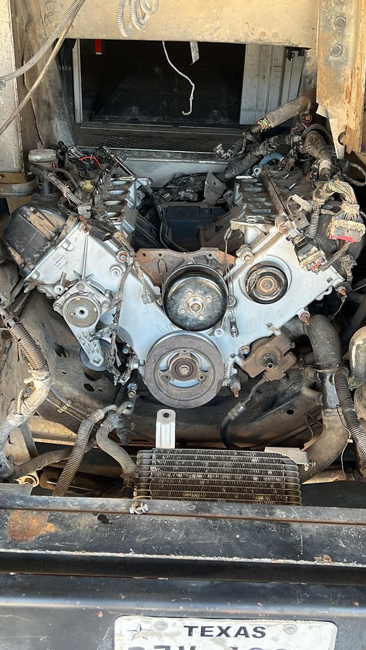 Severely damaged car engine, burnt and exposed, with Texas license plate visible.
