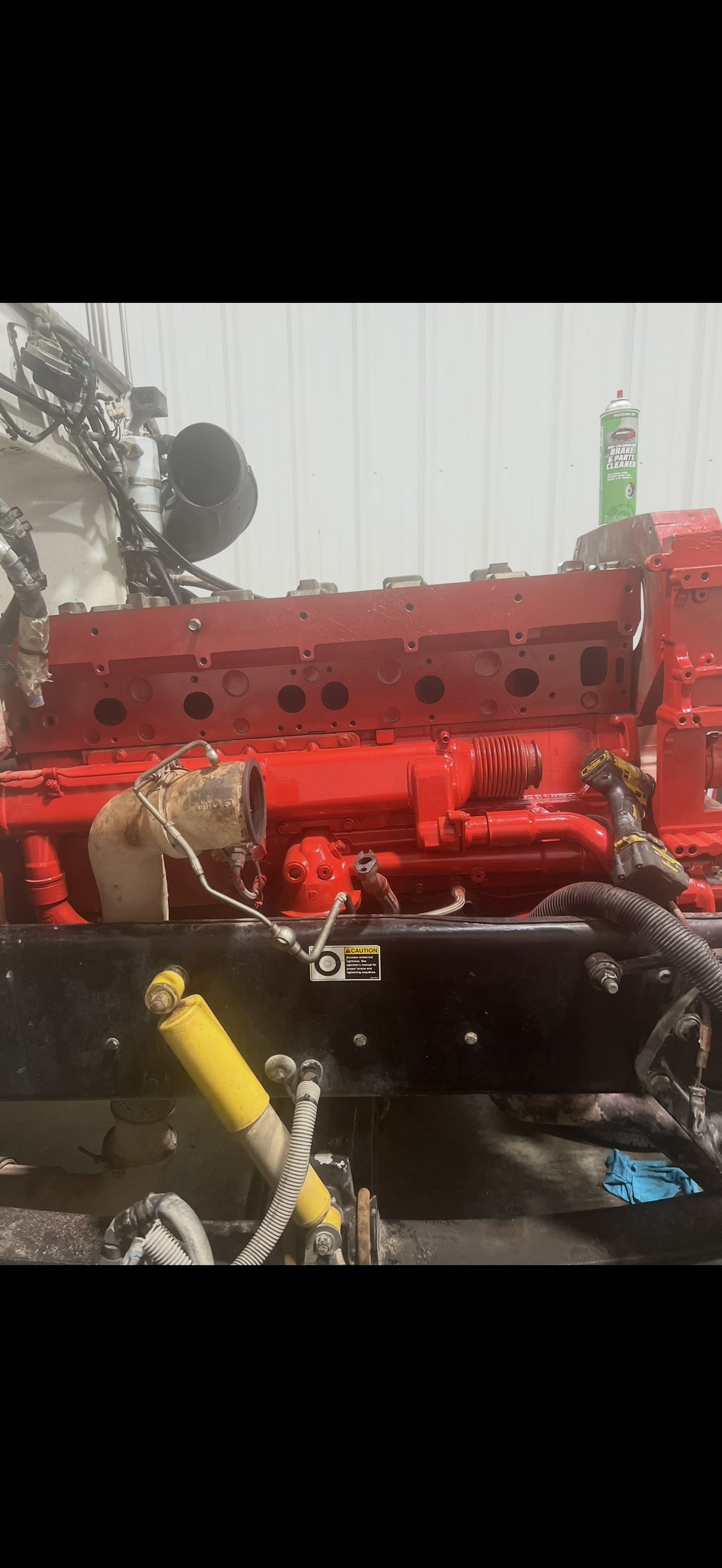 Red engine block, partially assembled, resting on a black frame. Yellow shock absorber is visible.