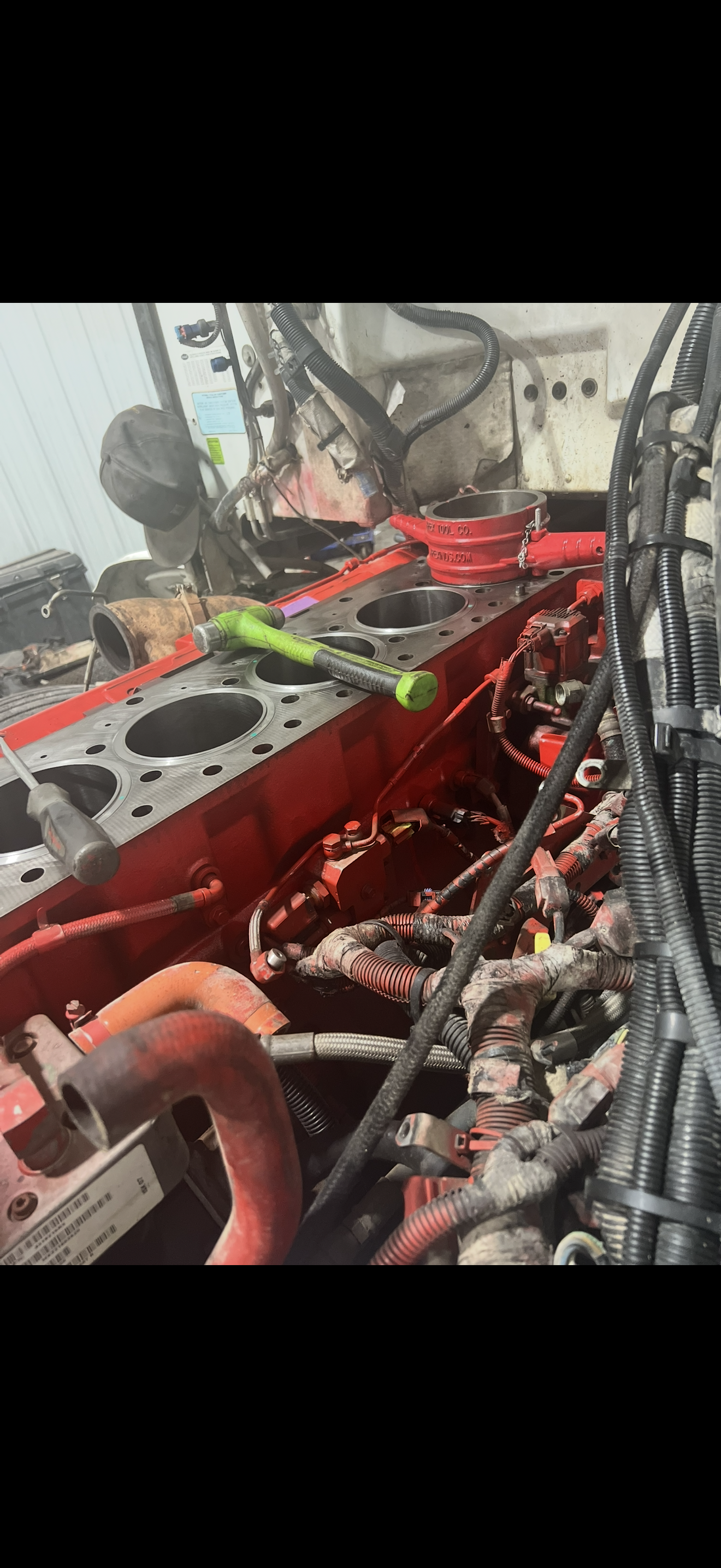 A truck engine being worked on, showing red components and tools.
