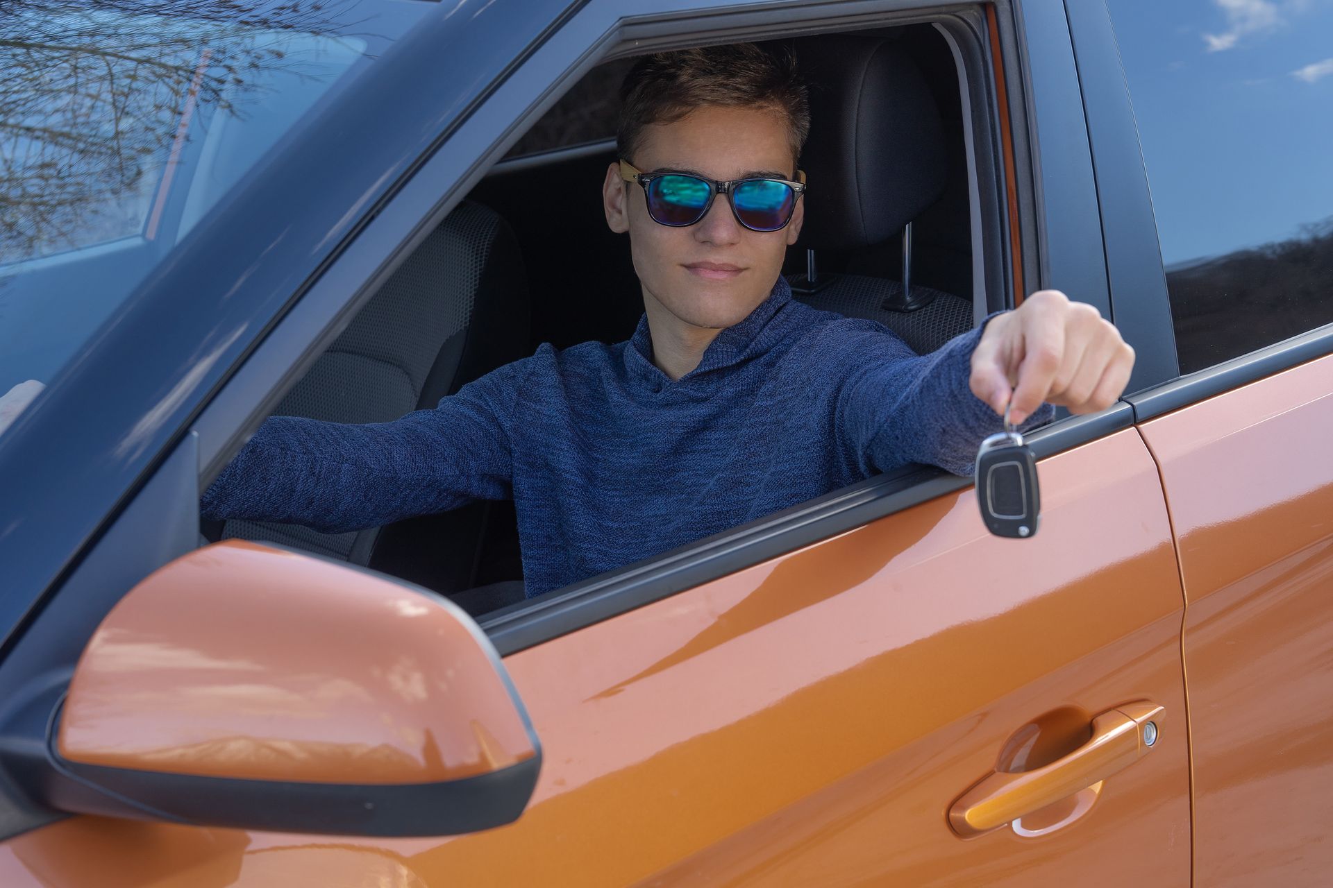 A teenager is sitting in new car and shows the key. A teenager is sitting in new car and shows the key.