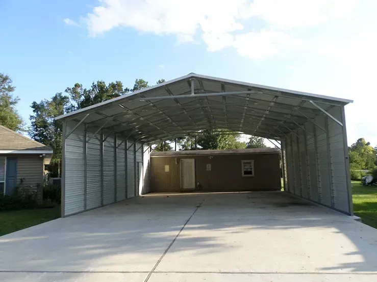A carport is attached to a house in a driveway.