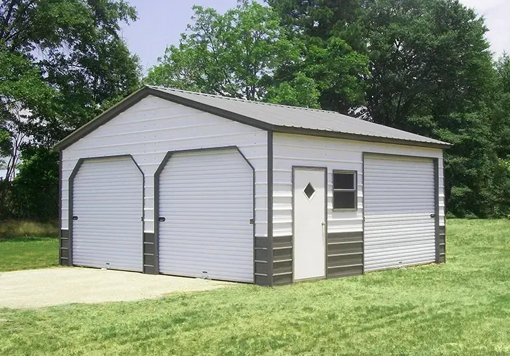 A white garage with two garage doors is sitting in the middle of a grassy field.
