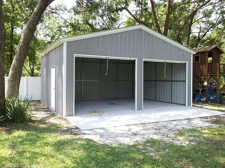 A gray metal garage with two doors in a backyard.
