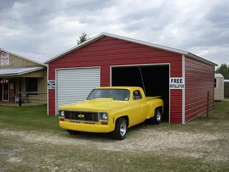 A yellow truck is parked in front of a red garage.