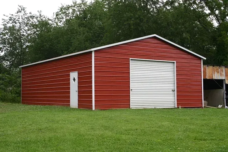A red barn with a white door is sitting in the middle of a grassy field.