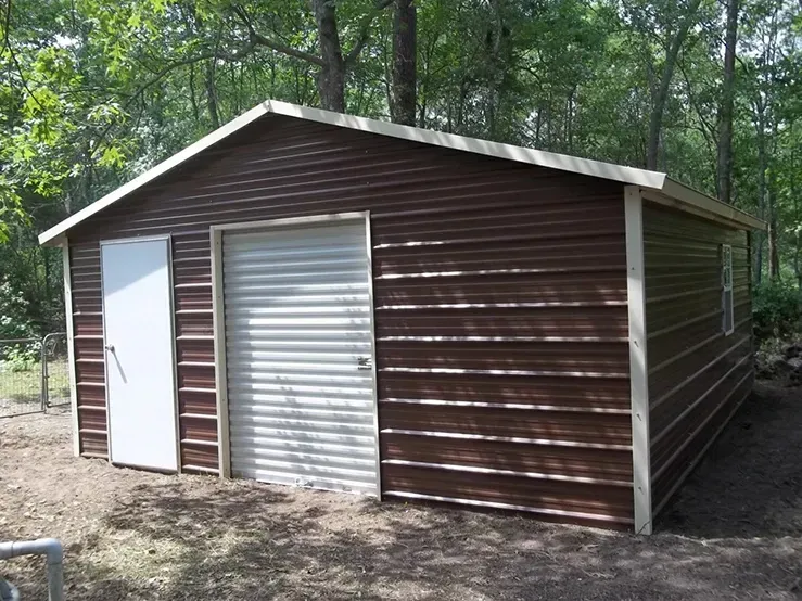 A brown garage with a white door is sitting in the middle of a forest.