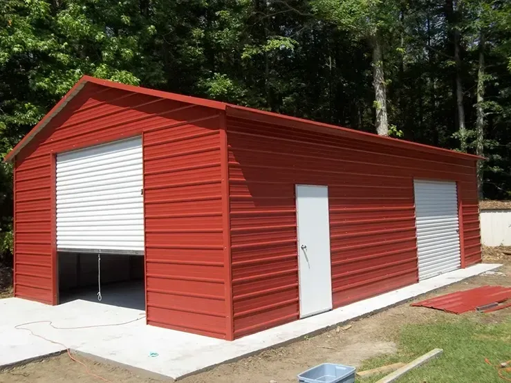 A red metal garage with white doors is being built in a backyard.