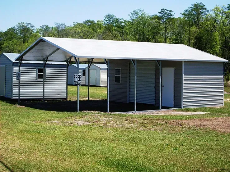 A shed with a canopy attached to it is sitting in the middle of a grassy field.