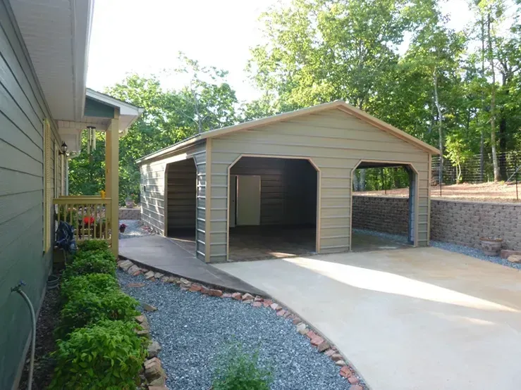 A garage with a driveway leading to it is next to a house.