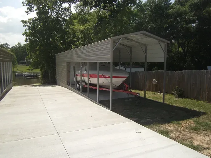 A boat is parked under a canopy in a driveway