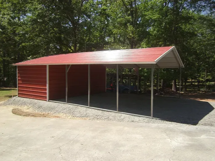 A red carport with a white roof is sitting on top of a gravel driveway.