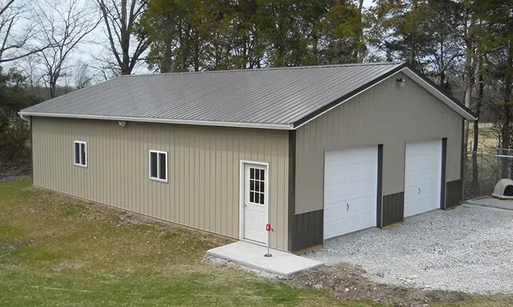 A large metal garage with two garage doors and a gray roof.
