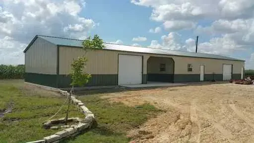 A large metal building is sitting in the middle of a dirt field.
