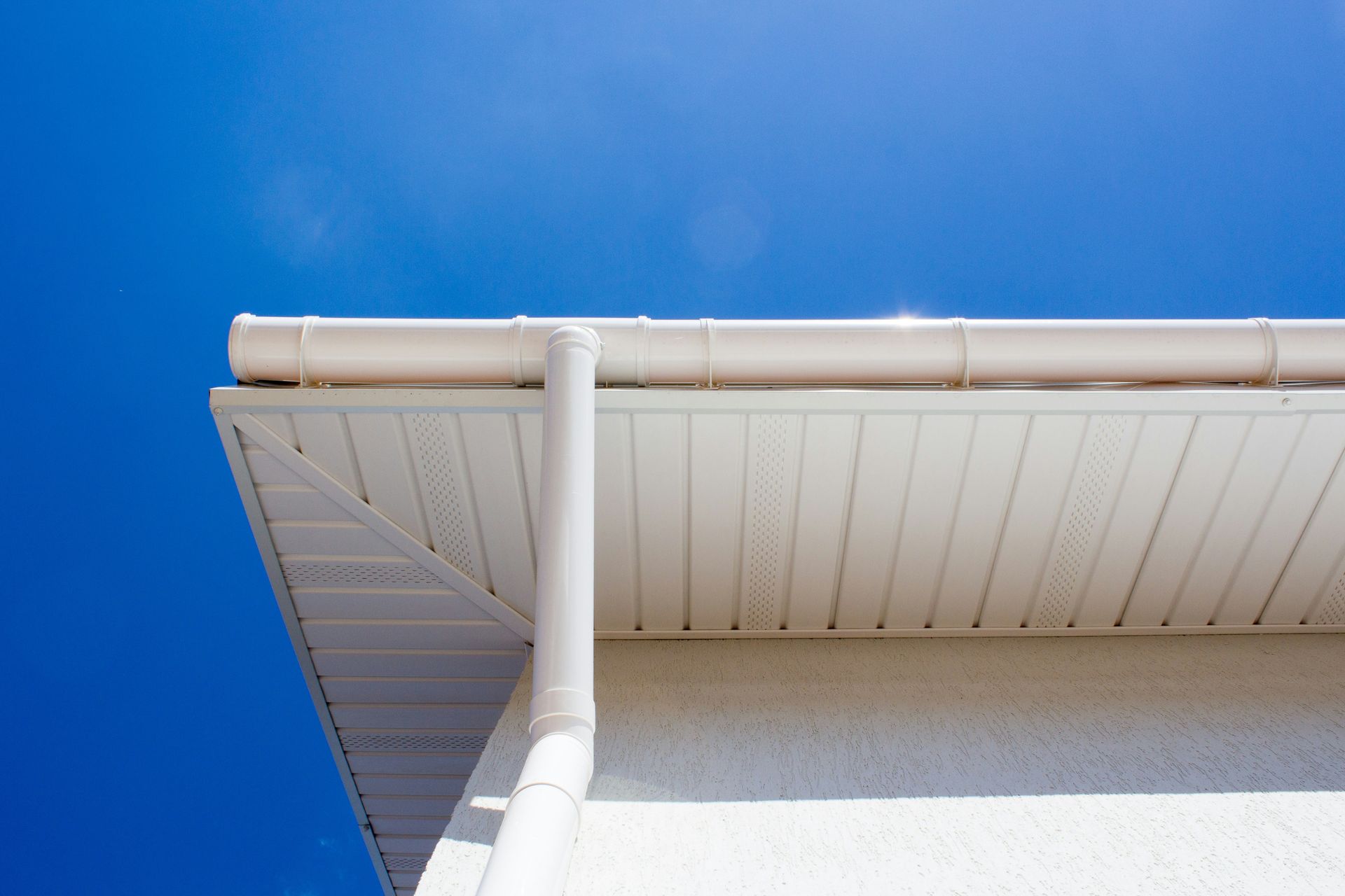 White house eaves and gutter against a bright blue sky