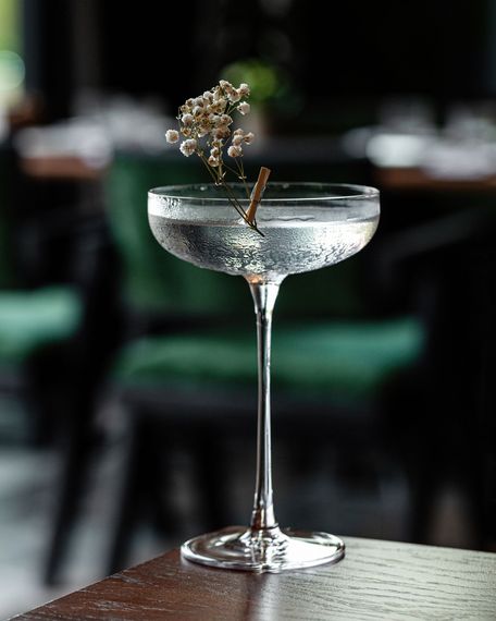 Su un tavolo c'è un bicchiere da martini con un fiore dentro.