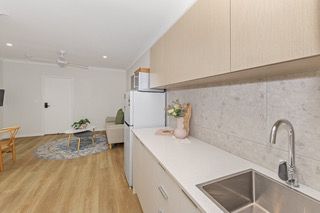 Kitchenette in a finished rooming house suite, with sink, fridge and overhead cupboards