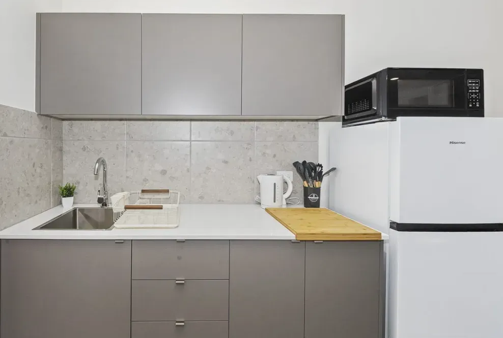 Kitchenette in a finished rooming house, with sink, microwave and fridge