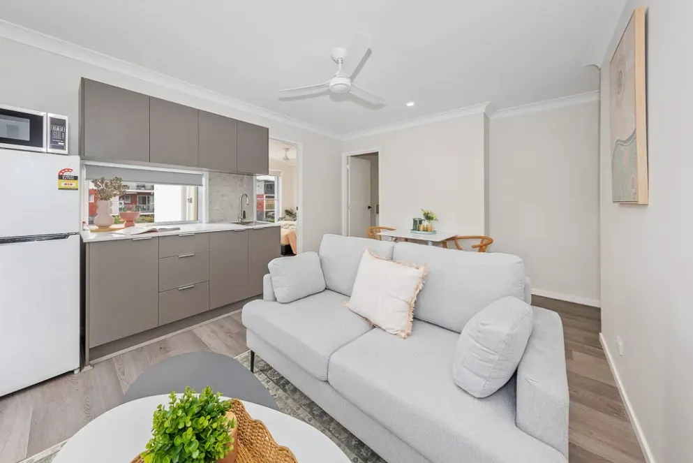 Living room with a grey sofa and the kitchen bench behind