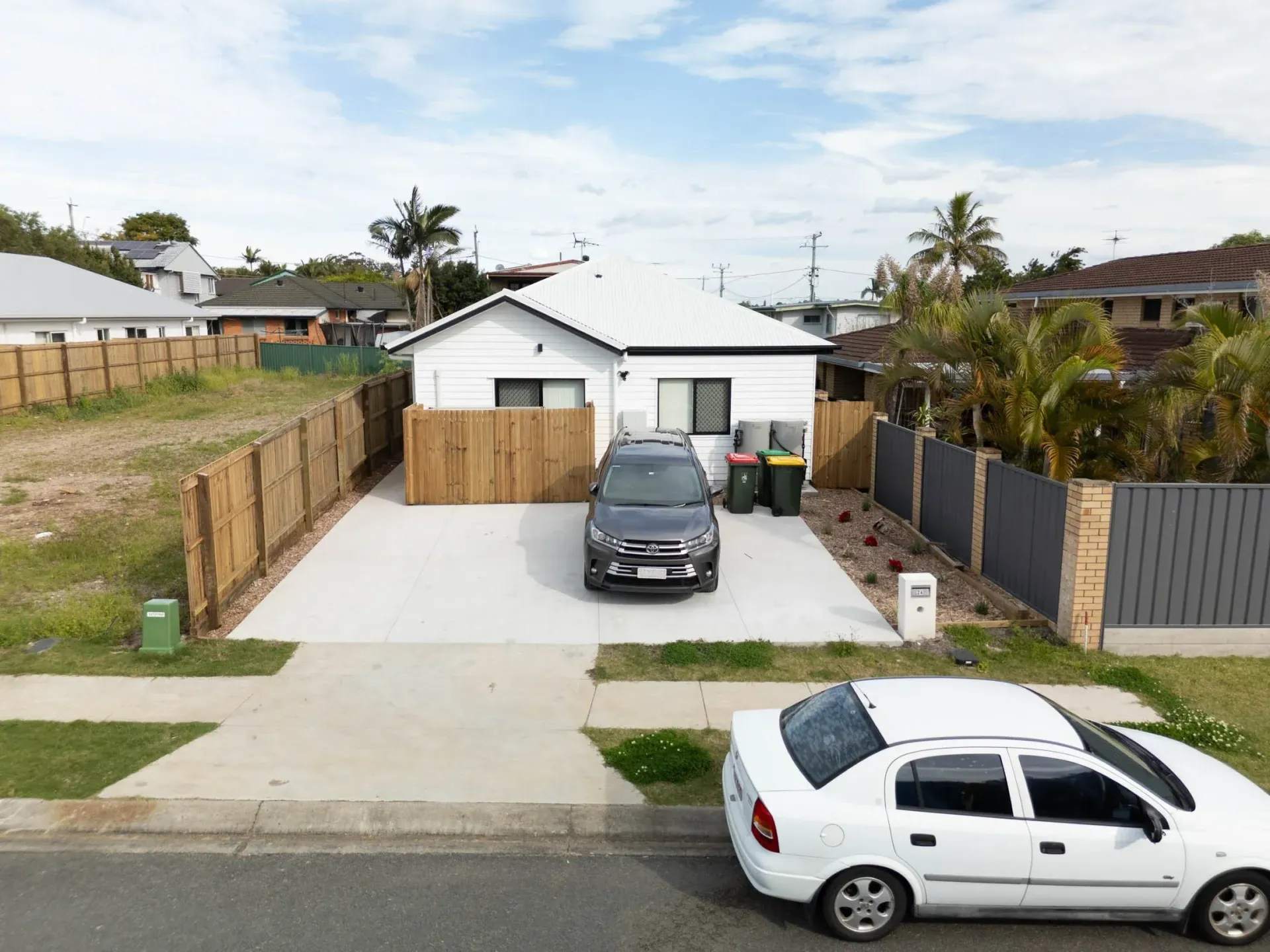 Completed rooming house seen from the street, with cars in the driveway