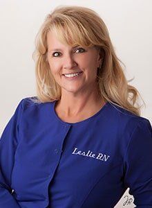 A woman in a blue scrub top is smiling for the camera.