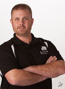 A man in a black shirt is standing with his arms crossed.