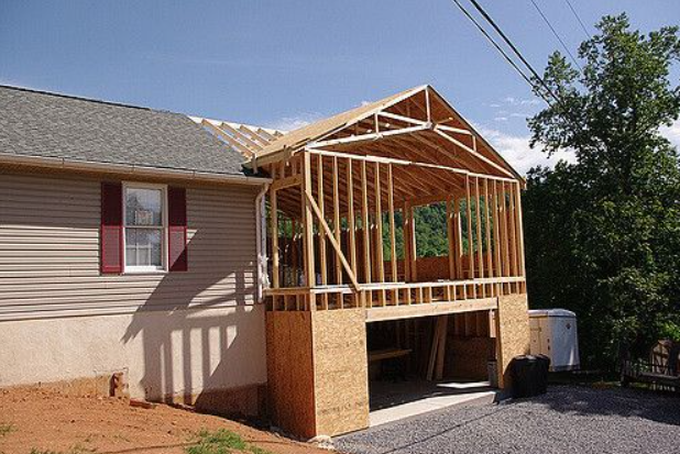 New wooden porch addition under construction beside a beige house