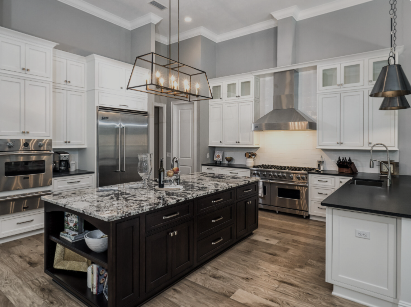 Modern kitchen with white cabinets, dark island, stainless appliances, and gray granite countertops