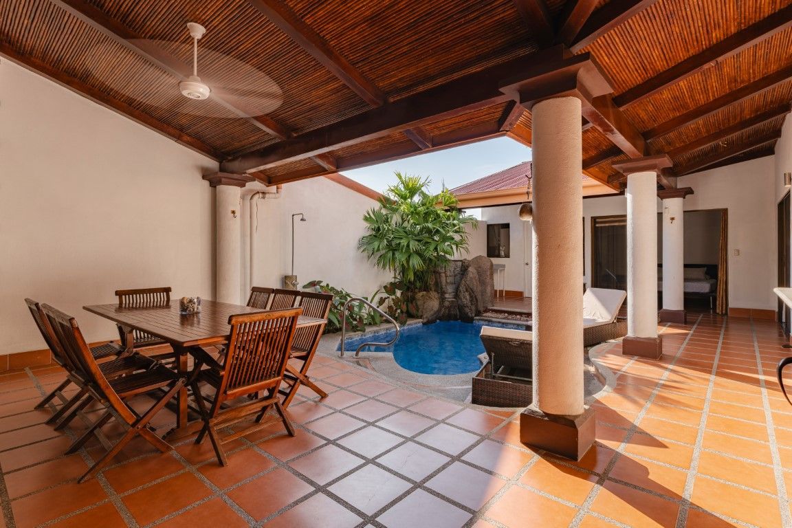 Covered patio with dining table, chairs, tiled floor, and a small pool surrounded by columns