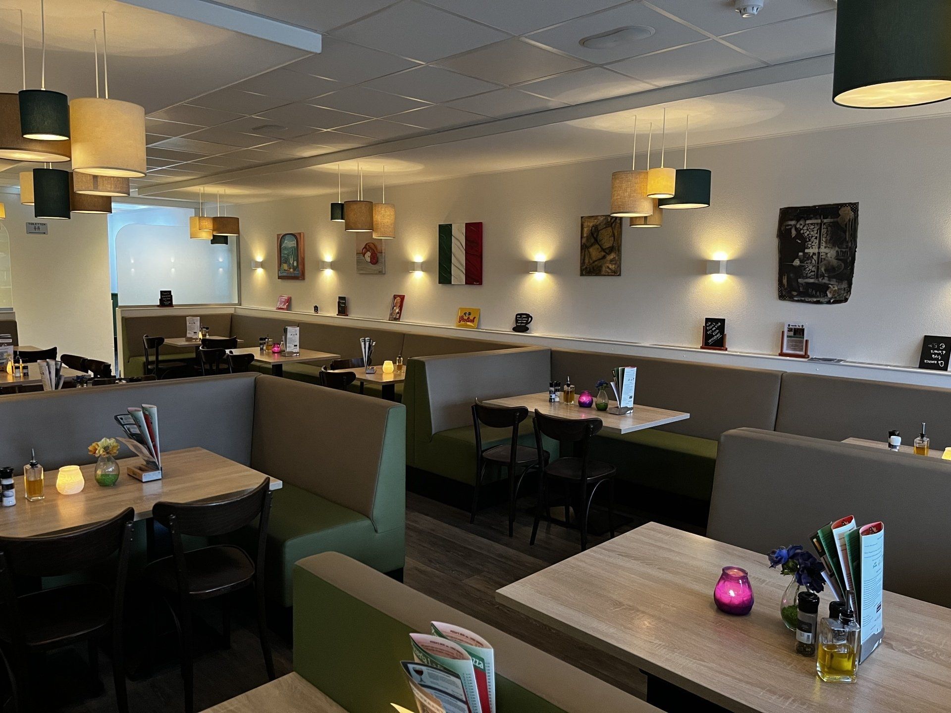 Rustige eetruimte in het restaurant met zitjes, houten tafels en sfeervolle hanglampen.