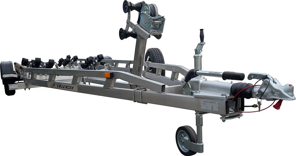 Silver boat trailer with rollers and winch, parked on pavement.