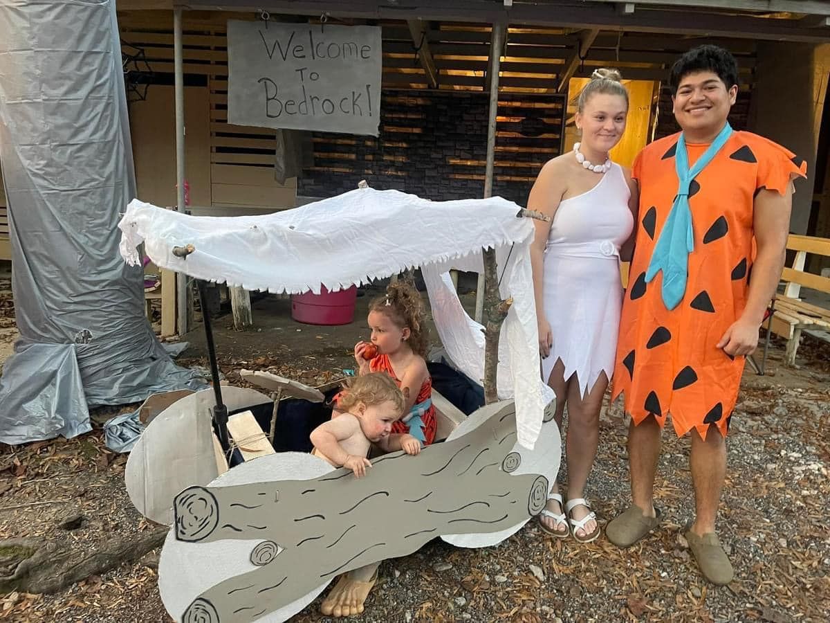 Two children and two adults in a handmade Flintstones-style car costume outdoors