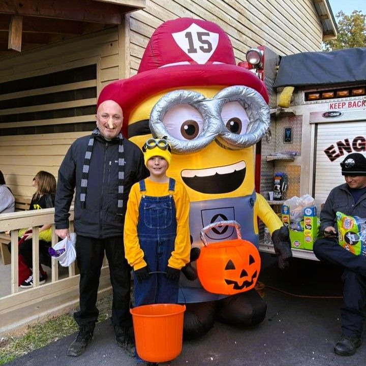 Two people posing with a large Minion Halloween display in front of a building.