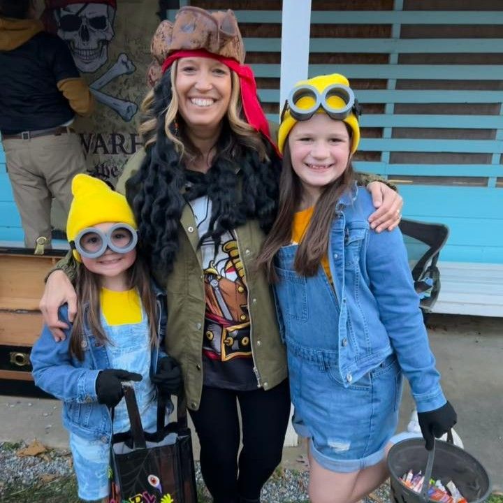 Three people in pirate and minion costumes smiling outdoors, holding buckets.