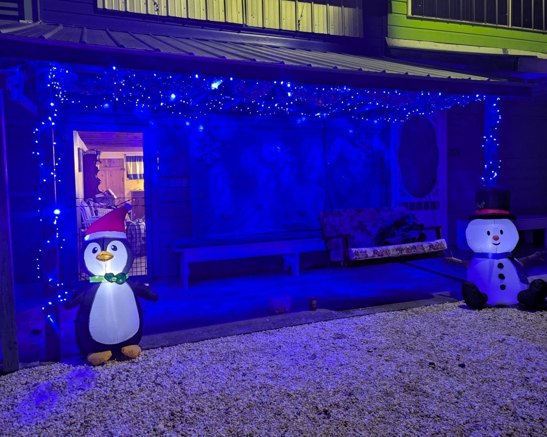 Blue-lit porch with two illuminated snowman decorations and string lights at night