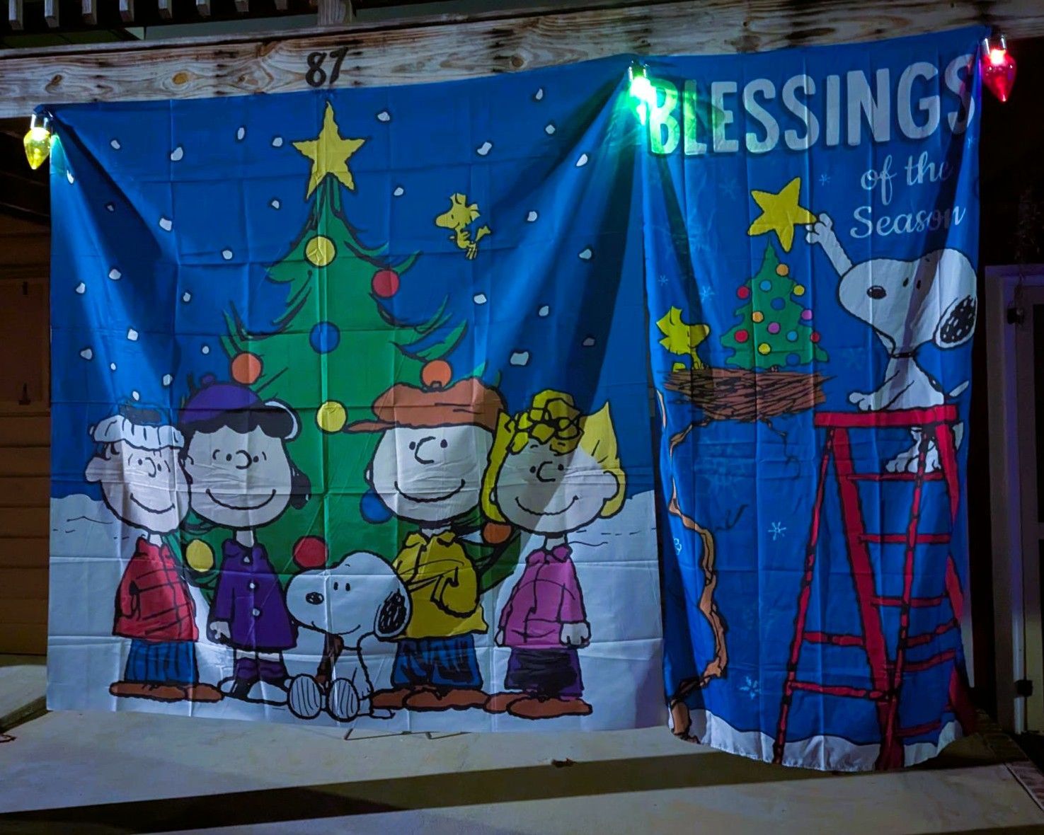 Holiday mural with Peanuts characters around a Christmas tree and “Blessings” text on a blue wall