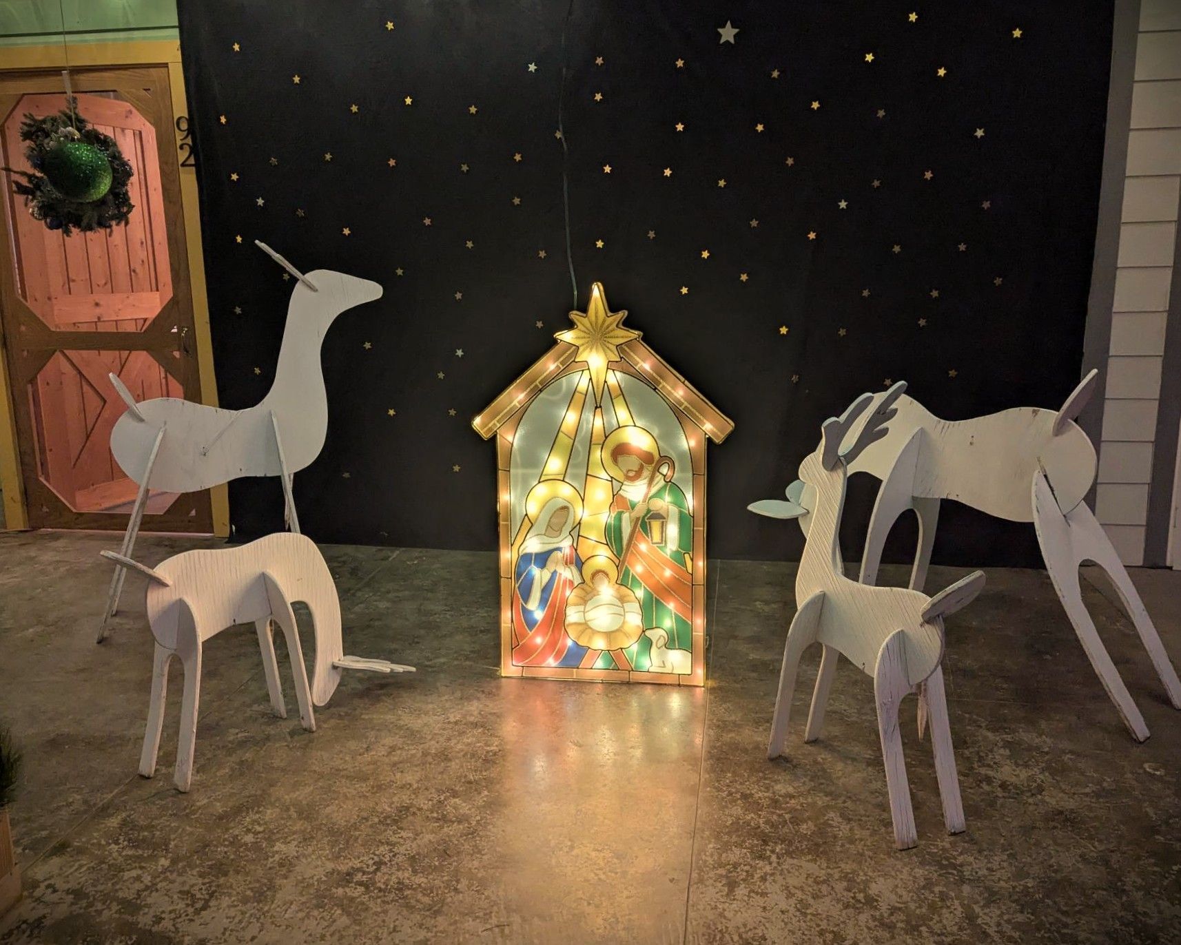 Nativity scene with glowing stable, white animal cutouts, and starry black backdrop