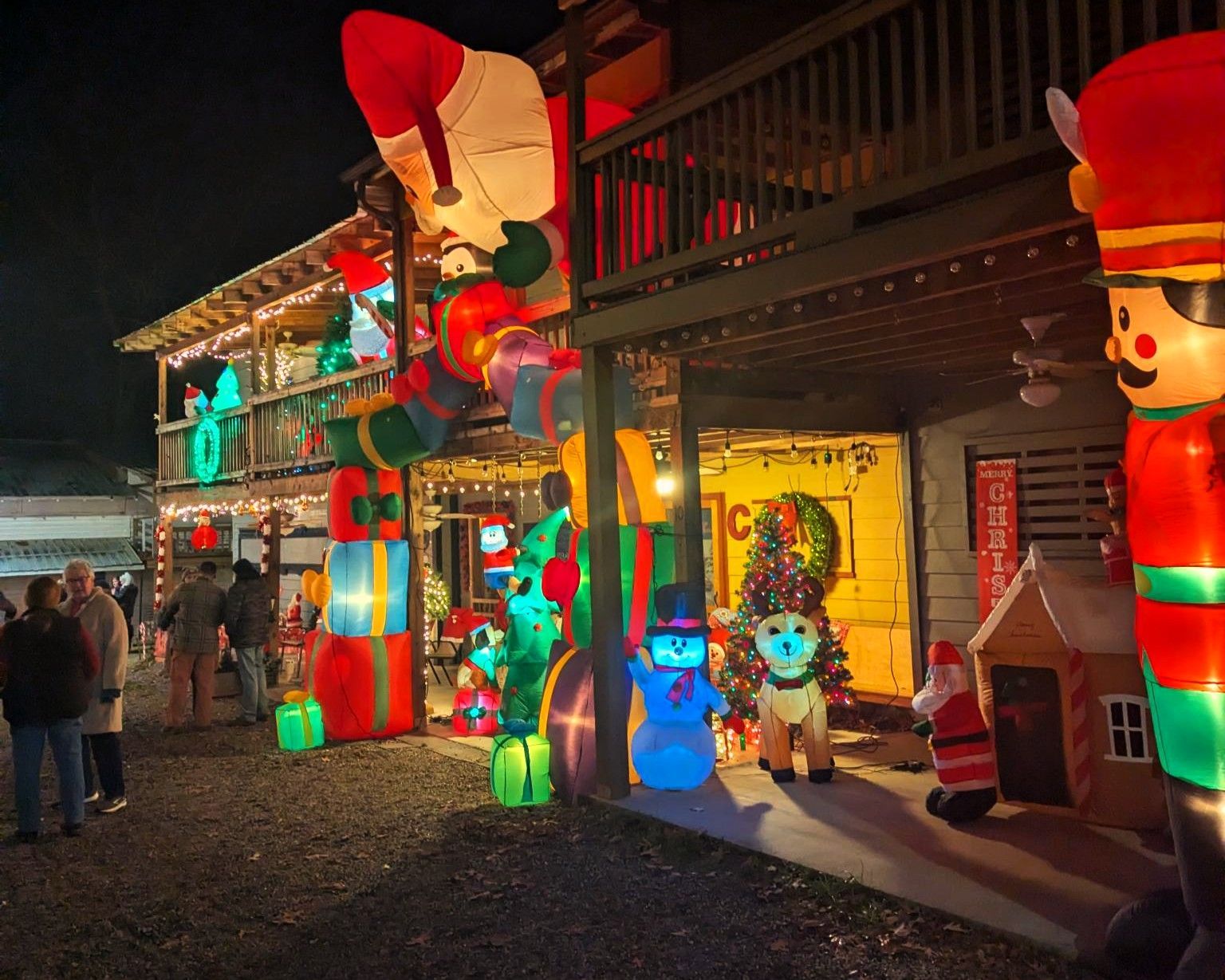 Colorful holiday light display with giant Santa figures and glowing decorations outside a building at night