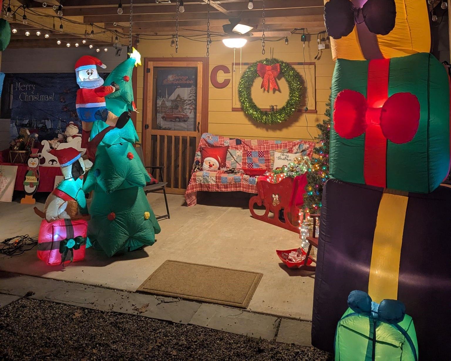 Christmas display with giant gift boxes, decorated trees, and a wreath in a festive indoor shop window