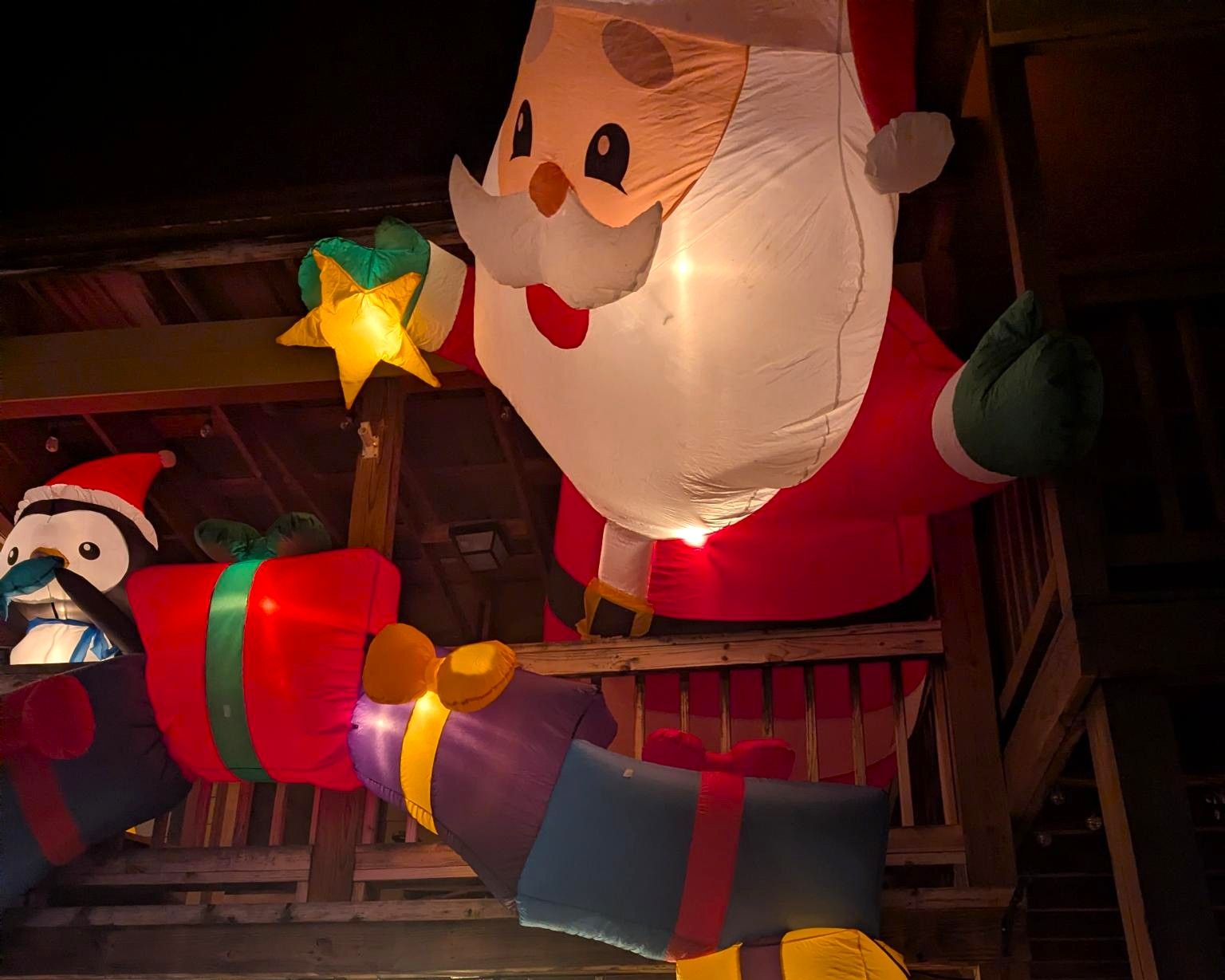 Inflatable Santa, snowman, and star holiday decorations lit up in a dark indoor space