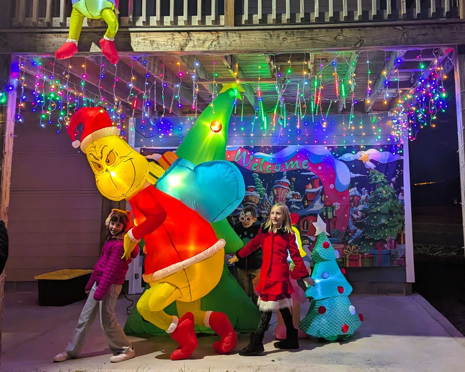 Colorful inflatable holiday figures and performers under string lights on a stage