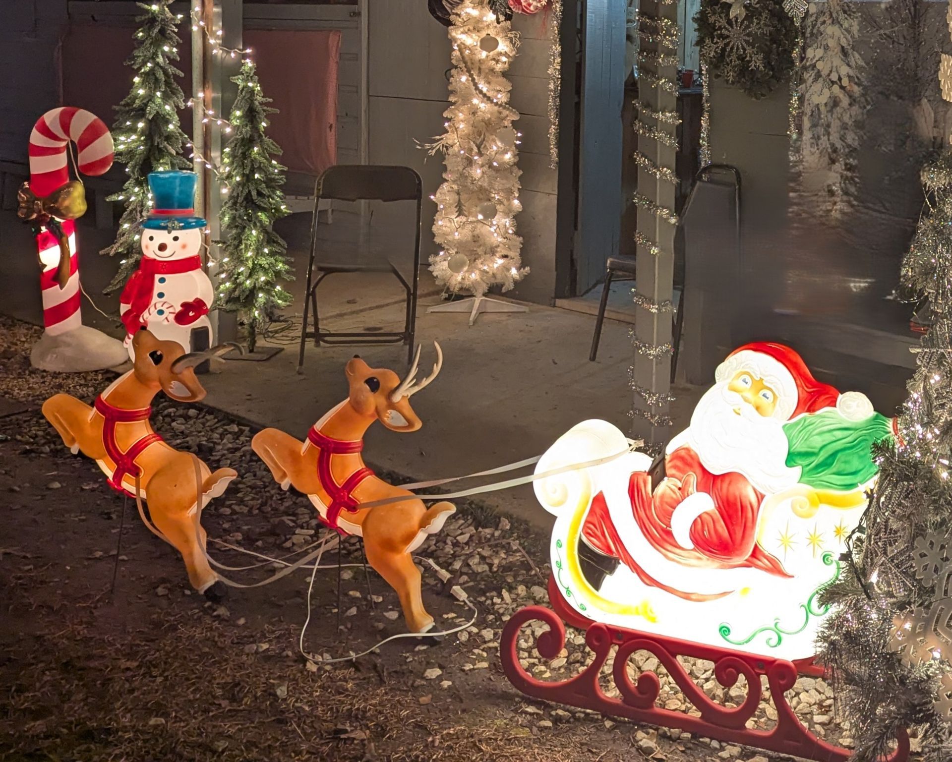 Christmas window display with lit Santa sleigh and two reindeer decorations outside a shop at night