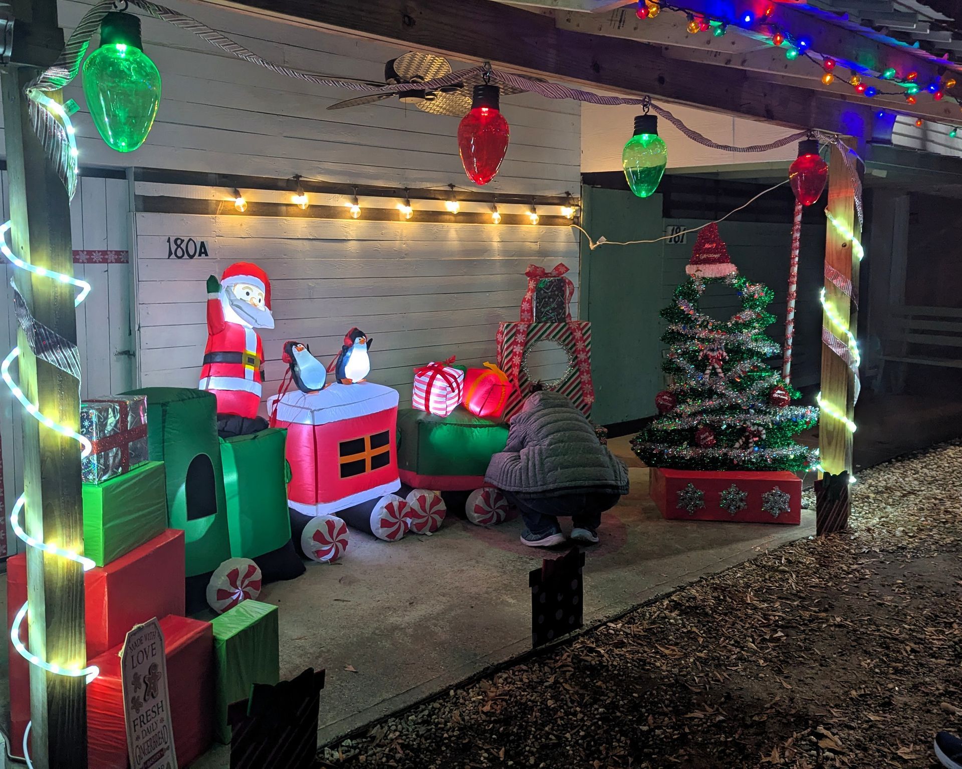 Festive porch with Christmas decorations, lit trees, and Santa-themed displays under colorful string lights