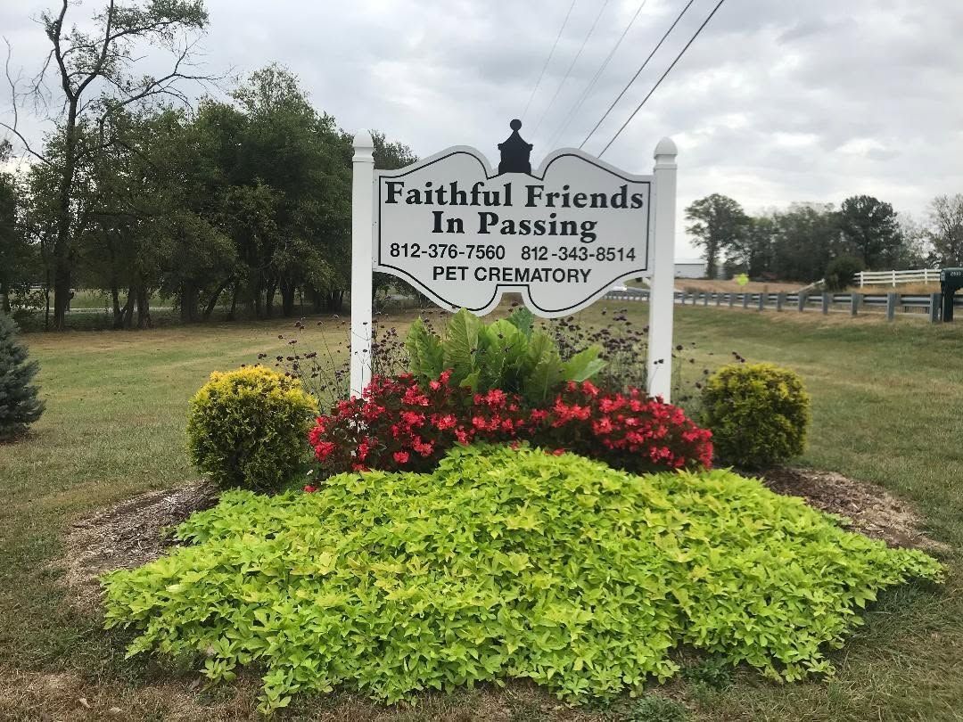 Faithful Friends Pet Passing memorial sign in a landscaped garden with red and yellow flowers