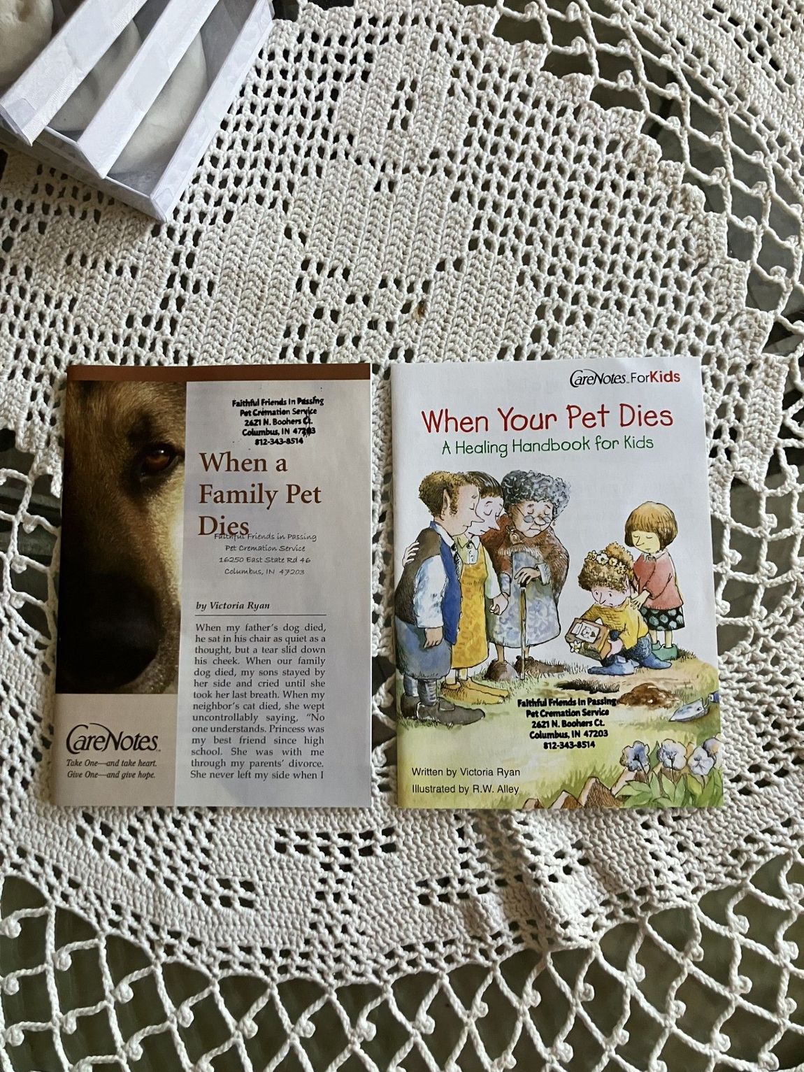 Two children’s books open on a lace tablecloth, one titled “When a Family Pet Dies” and the other “What If Your Pet Dies?”