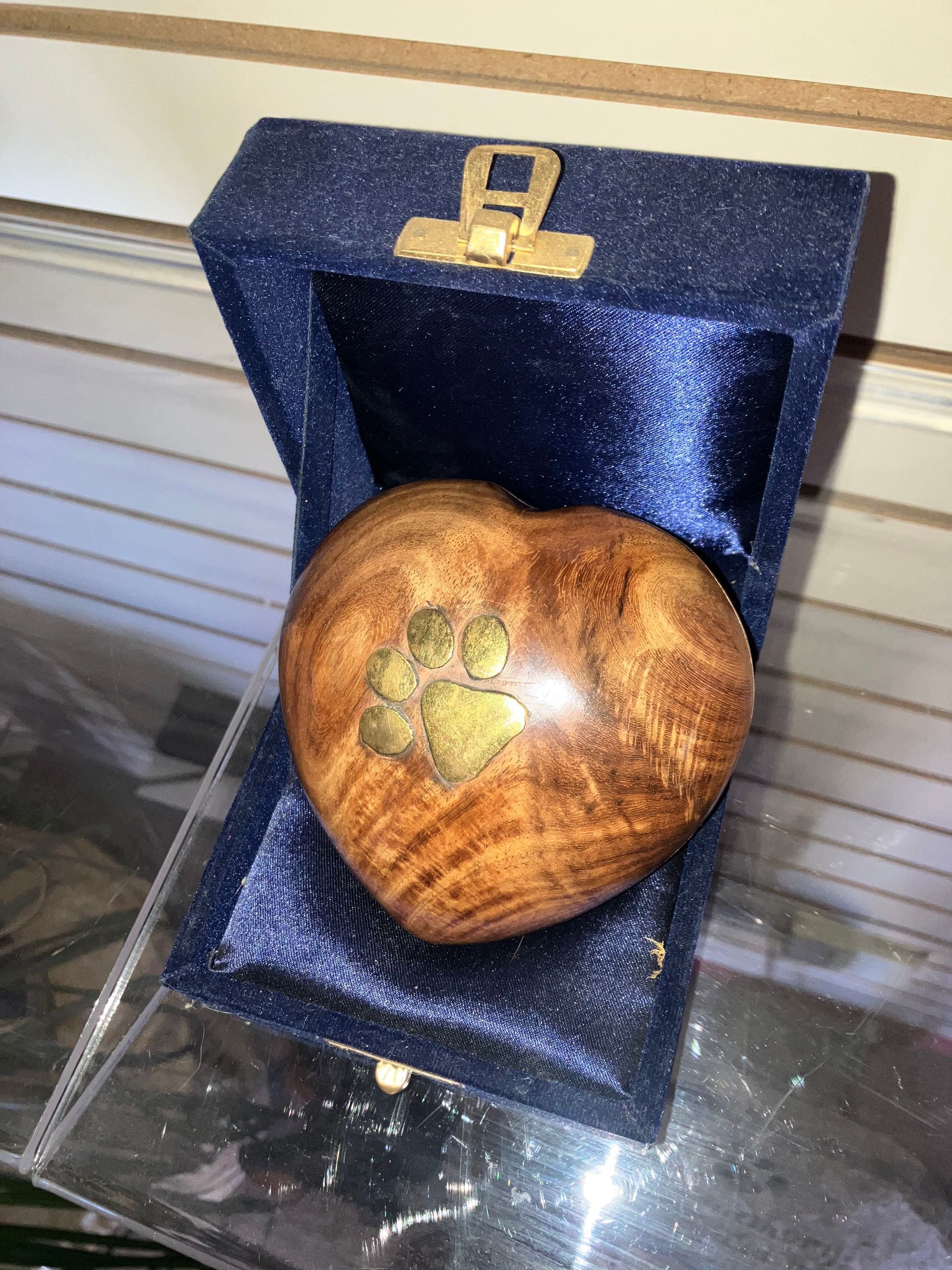 Heart-shaped wooden box with a brass cross on a dark blue velvet display stand