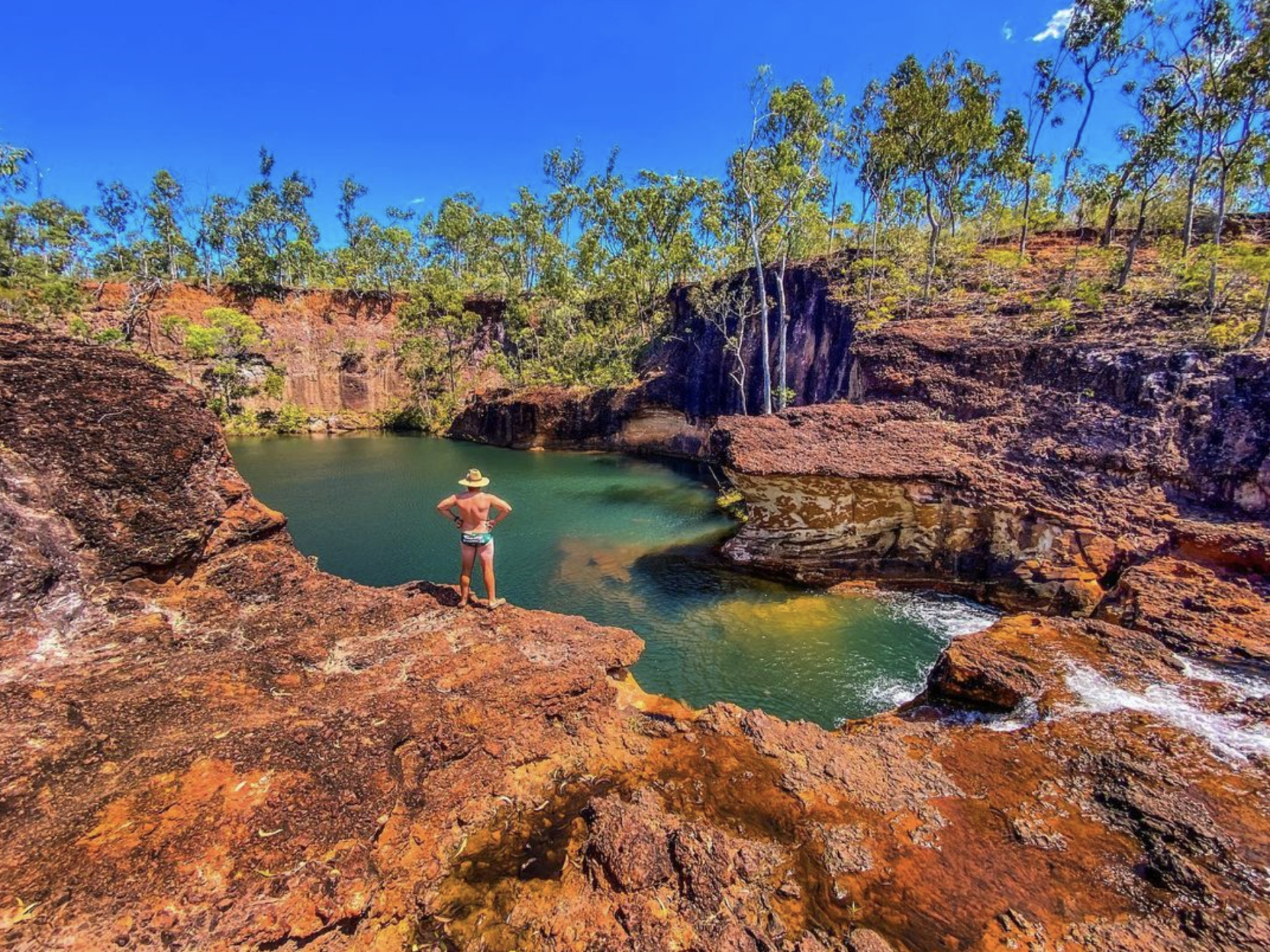 A man is standing on a cliff overlooking a lake.